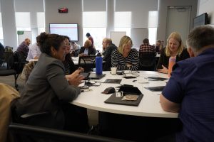A group of university staff members having a discussion while sitting around an active learning classroom table in the LR Wilson building at McMaster University.